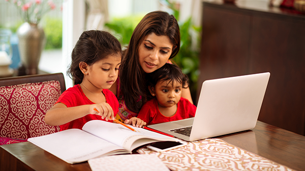 a mother sitting at her computer with her two children